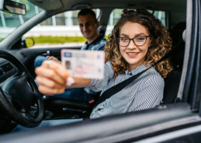 Portrait of a female student passing her driving test after a young driving instructor graded her. Holding her new driver's licence.